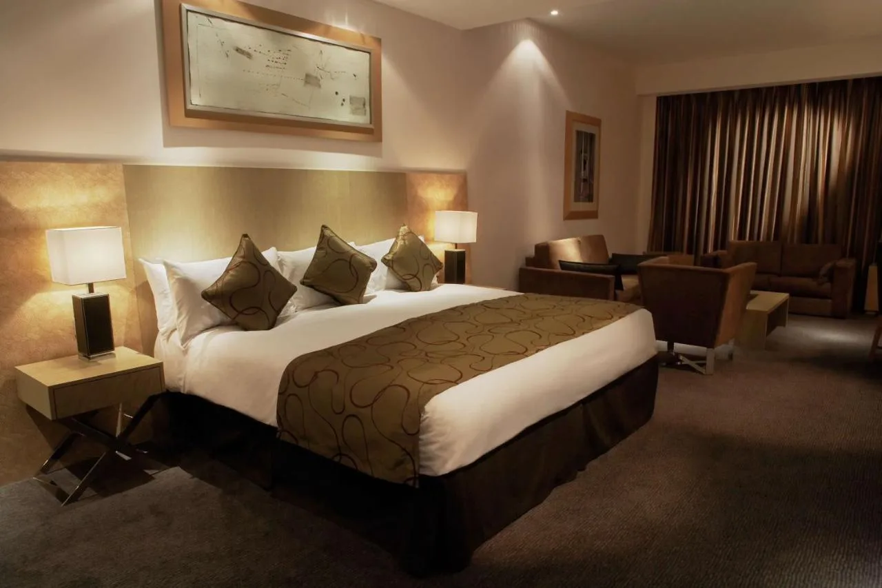 a hotel room with a large bed and a living room at Park Plaza Cardiff in Cardiff